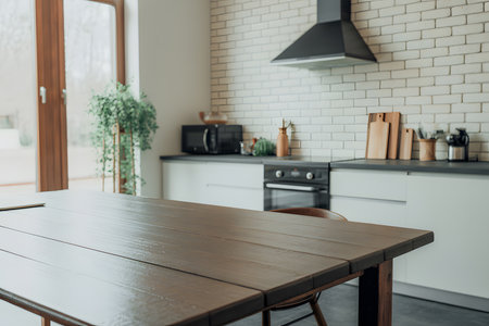 Modern minimalist kitchen with rustic wooden table, white cabinets, black appliances, and airy natural light. Perfect blend of style and functionality.の素材