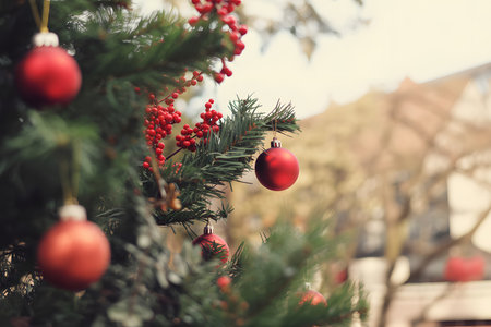 Charming close-up of red glass ornaments and holly berries on pine branches, featuring a dreamy bokeh background for a vintage holiday vibe. Soft, natural lighting enhances the festive spirit.の素材