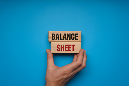 Minimalist flat lay of wooden blocks 'BALANCE' and 'SHEET' on vibrant blue background, symbolizing business strategy and organization in a professional setting.の素材