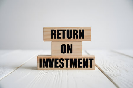Minimalist wooden blocks stacked with 'RETURN ON INVESTMENT' in bold text, set on a white wood surface. Ideal for business, finance, or investment themes.の素材