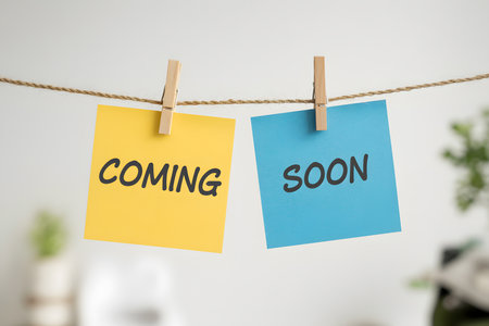 Photorealistic sticky notes 'COMING' and 'SOON' hanging on string with clothespins, set against a soft white bokeh background. Perfect for various themes.の素材
