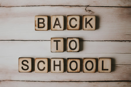 Minimalist back-to-school scene featuring stacked wooden blocks with 'BACK TO SCHOOL' text, arranged on a light wooden surface with school supplies for a clean, modern look.の素材