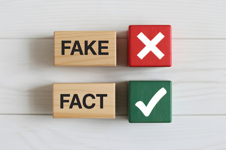 Flat lay of wooden blocks labeled FAKE and FACT, alongside red X and green checkmark symbols, on a white wooden background. Minimalist and clean design.の素材