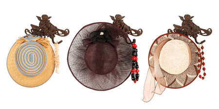 female hats on hooks in front of white backgroundの写真素材