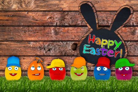 funny eater eggs in front of wooden easter backgroundの写真素材