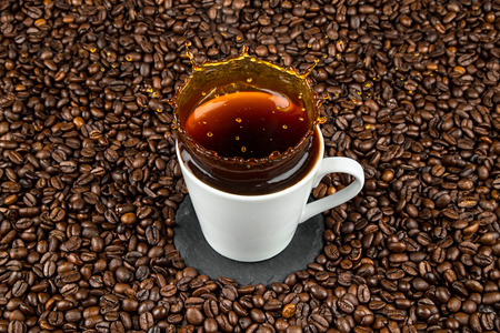 coffee cup splash on coffee beansの写真素材