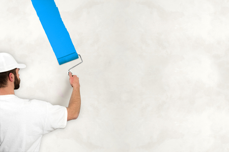 young man painting wall with blue colorの写真素材