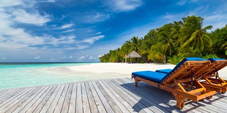 deckchairs on jetty in front of tropical islandの写真素材