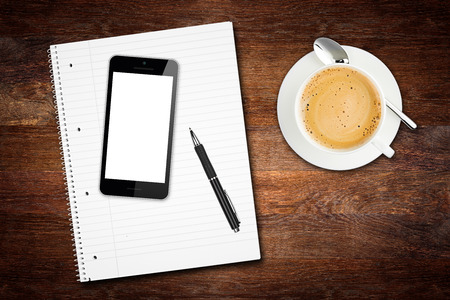 wooden desktop tabletop view break concept with notepad smart phone pen and coffee cupの写真素材