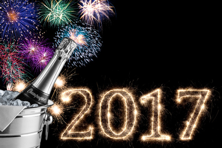 2017 colorful fireworks champagne bottle and cooler in the dark night sky with sparkling glowing...