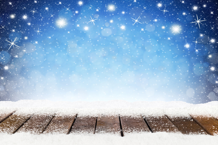 christmas xmas background with wooden snowy planks in front of blue night sky with stars and snowflakesの写真素材