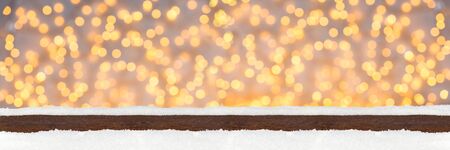 wide panorama banner christmas xmas background with wooden snowy planks in front of bright illuminated lights bokehの写真素材