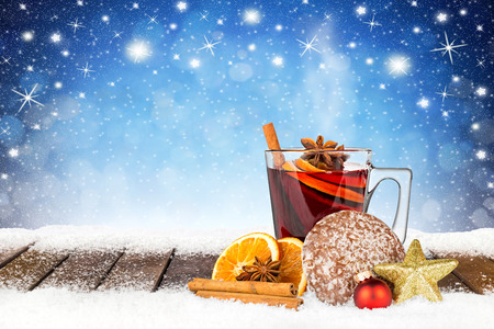 hot spiced mulled wine on wooden snowy planks in front of blue night sky with stars and snowflakes backgroundの写真素材