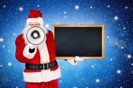traditional classic red white santa claus making shouting loud announcement with bullhorn megaphone wooden blackboard in his other hand in front of holy night blue stars sky backgroundの写真素材