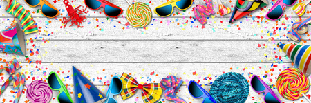 colorful wide panorama party carnival birthday celebration background with colorful streamer candy lolly pop sunglasses confetti hat lolly pop on white woodの写真素材