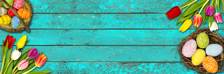colorful wooden easter background tulips eggs nest basket on rustic old oak turquoise blue wood textureの写真素材