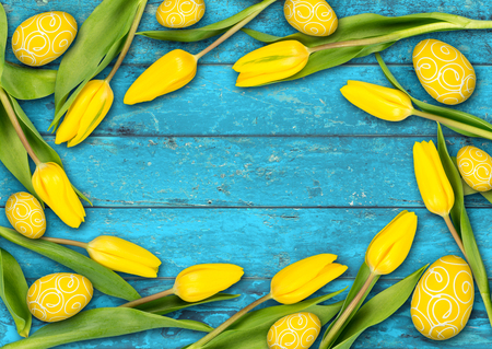colorful wooden easter background yellow tulips eggs  on rustic old oak turquoise light blue wood textureの写真素材