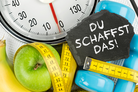 fitness diet motivation background concept apple banana measuring tape and slate on white bathroom scaleの写真素材