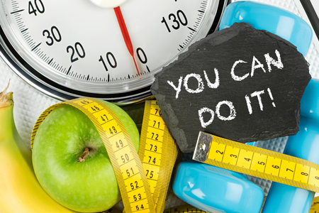 fitness diet motivation background concept apple banana measuring tape and slate on white bathroom scaleの写真素材