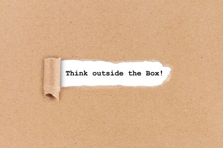 think outside the box business concept ripped hole in brown paper on white backgroundの写真素材
