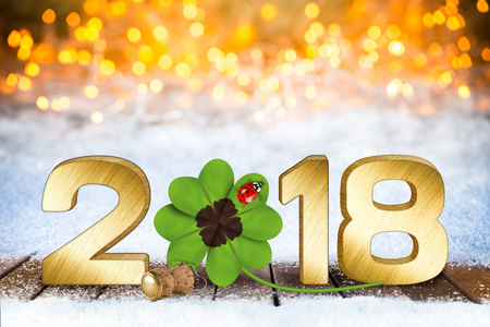 happy new years eve silvester golden 2018 number with four-leaf clover and ladybug in front of bright bokeh background on snowの写真素材