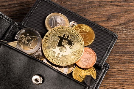 golden bitcoin crypto currency coin on euro coins in leather wallet on wooden backgroundの写真素材