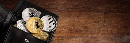 crypto currency coin in black leather wallet on wide wood wooden panorama background with copy space bitcoin ethereum litecoin iota rippleの写真素材