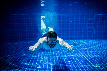 young man with sunglasses enjoying the swimming pool abstract summer fun underwater swimming jump diving backgroundの写真素材