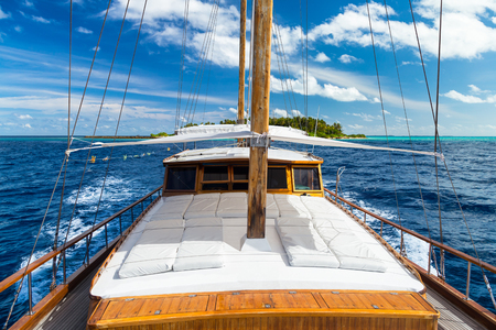 luxury sailing boat yacht in front of tropical paradise maldives island resort with coral reef and turquoise blue ocean water tourism backgroundの写真素材
