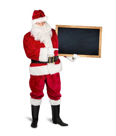 classic traditional red santa claus holding empty wooden slate blackboard chalkboark pointing with finger on it. blank slate with copy space isolated on white christmas advertising backgroundの写真素材