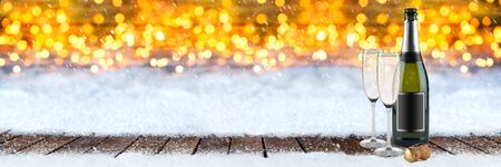 happy new year greeting wide panorama background with bottle of champagne glasses cork on wooden planks in front of bright golden warm bokeh light backgroundの写真素材