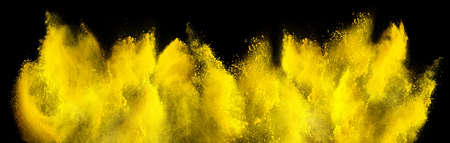 yellow holi paint color powder explosion isolated on dark black background. industry beautiful party...
