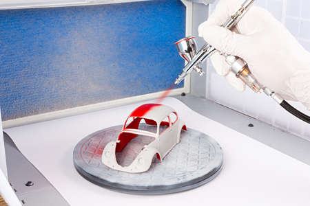 paint job with metal chrome airbrush spray paint gun on red retro scale model retro vintage car in...