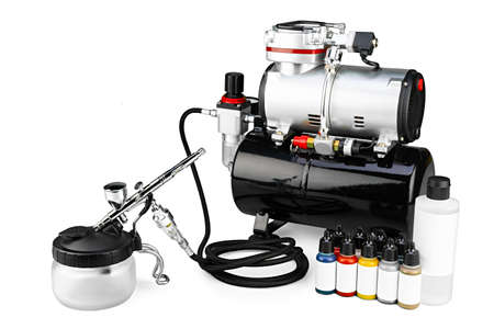 professional airbrush compressor starter set equipment with chrome metal gun acrylic paint and thinner bottles isolated on white background. Industry hobby and art concept.の写真素材