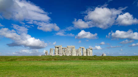 world famous stonhenge prehistoric stone circle monument on blue skygreen grass sunny backgroundの写真素材