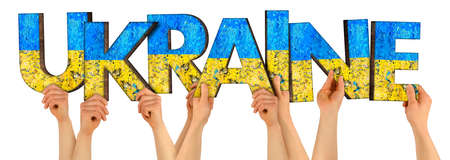 people arms hands holding up wooden letter lettering forming word UKRAINE in ukrainian national flag colors blue and yellow. war peace freedom and patriotism concept isolated on white backgroundの写真素材