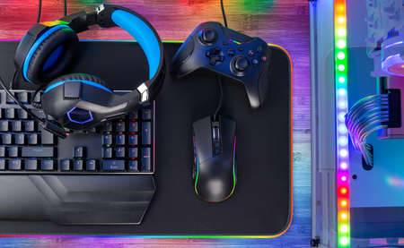 Top view of a colorful bright pc rgb LED gaming desk with headset keyboard mouse and desktop computer. esports technology concept backgroundの写真素材