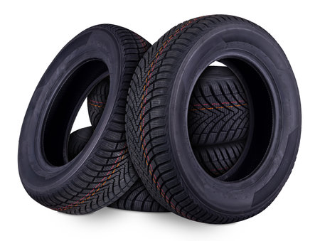 four new all weather season or winter tires car tires stacked isolated on white background. Road safety and transportation service conceptの写真素材