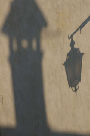 Shadows of a chimney and an old lamp on a  wall