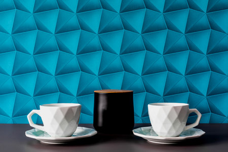 A background with blue wallpaper - colorful space. Black containers for storing sugar, tea or coffee with a wooden lid. Organization and order in the house.の写真素材