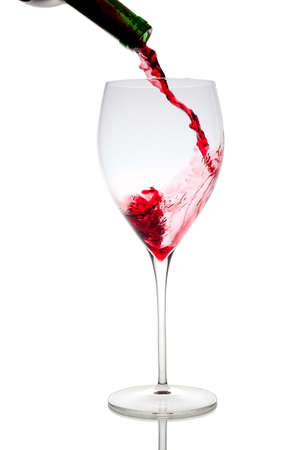 Pouring red wine in glass goblet isolated on whiteの写真素材