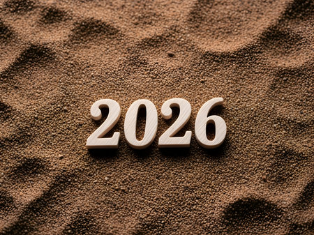 The year 2026 is displayed in wooden numbers on a textured brown surface, symbolizing the upcoming year and future expectationsの素材