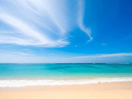Vibrant turquoise ocean water meets a sandy beach under a bright blue sky with wispy white cirrus clouds overhead, creating a perfect tropical seascapeの素材