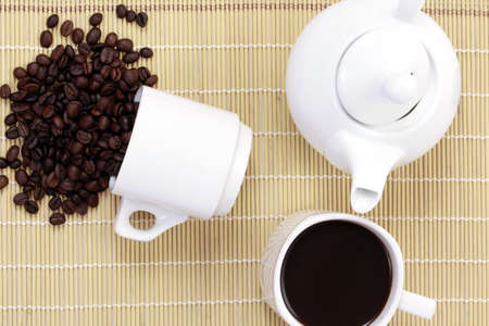 coffee cup and spilled coffee beans, in bamboo background
