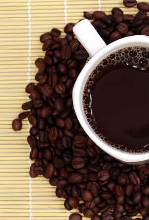 Cup of coffee sitting on coffee beans の写真素材