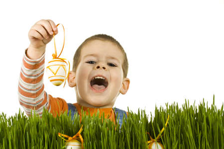 Easter egg hunt, boy searching for easter eggs hidden in fresh green grass