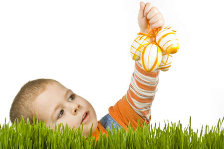Easter egg hunt, boy searching for easter eggs hidden in fresh green grass