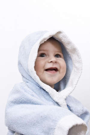 A beautiful smiling baby wrapped in a light blue blanketの写真素材