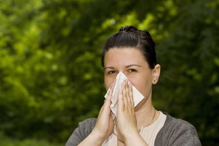brunette woman having a pollen allergy in the forestの写真素材