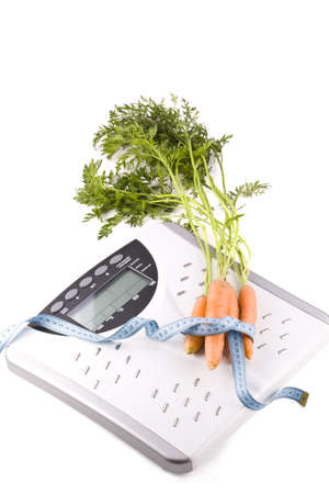 Carrots surrounded by a measuring tape on a white bathroom scale. Blank display. の写真素材